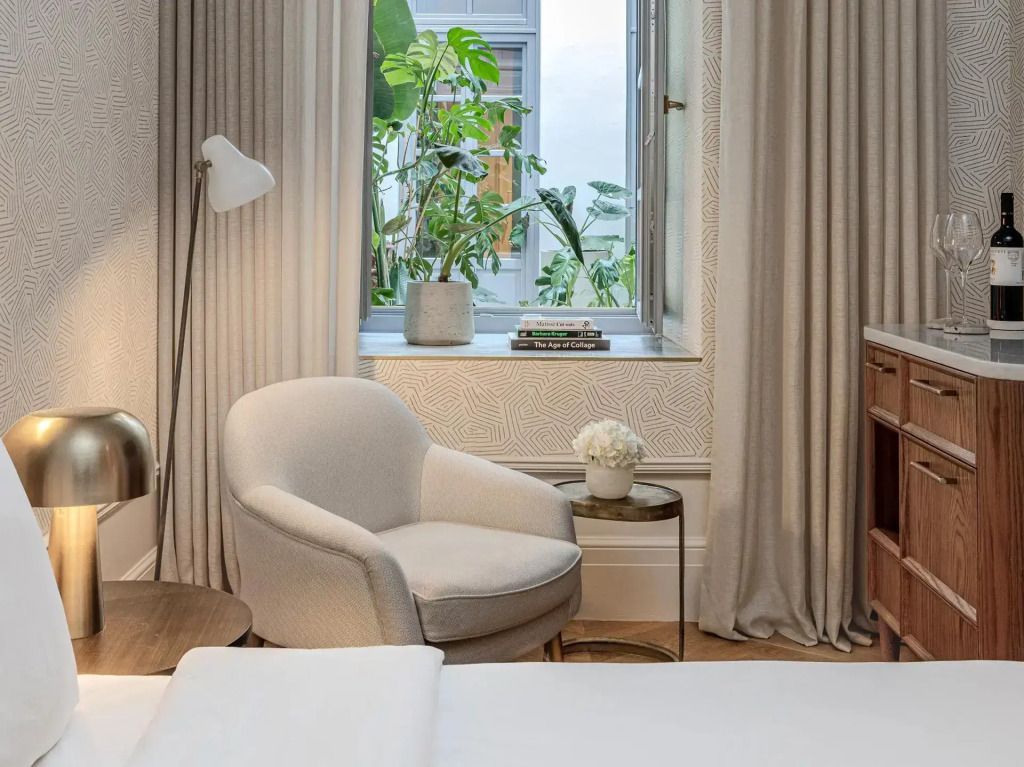 Gemütlicher Sessel neben dem Fenster mit Vorhängen und Pflanzen.