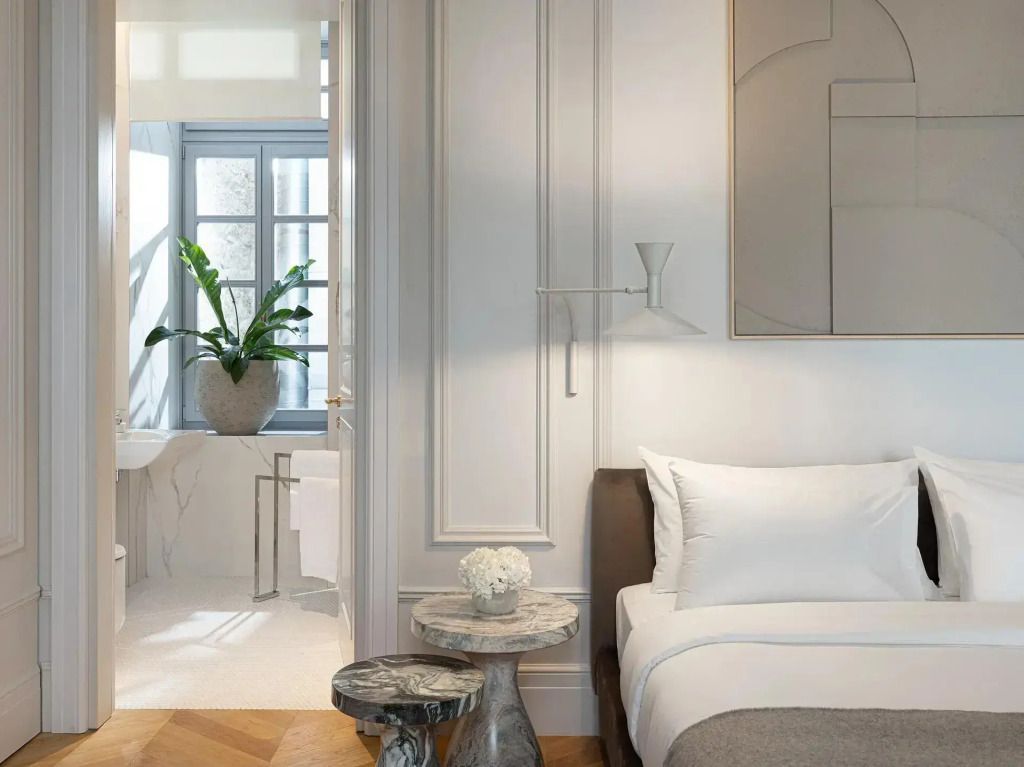 Schlafzimmer mit Marmorakzenten, modernem Kunstwerk und Blick ins Badezimmer