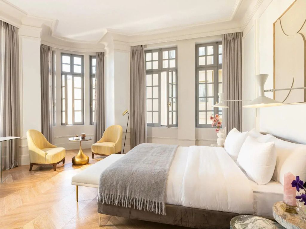 Großzügige Suite mit Erkerfenstern, Doppelbett und eleganten Sitzmöbeln.