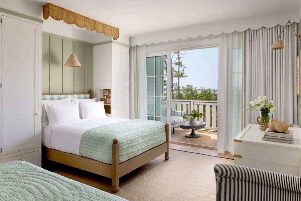 Helles Schlafzimmer mit zwei Betten und Zugang zu einem Balkon mit Meerblick
