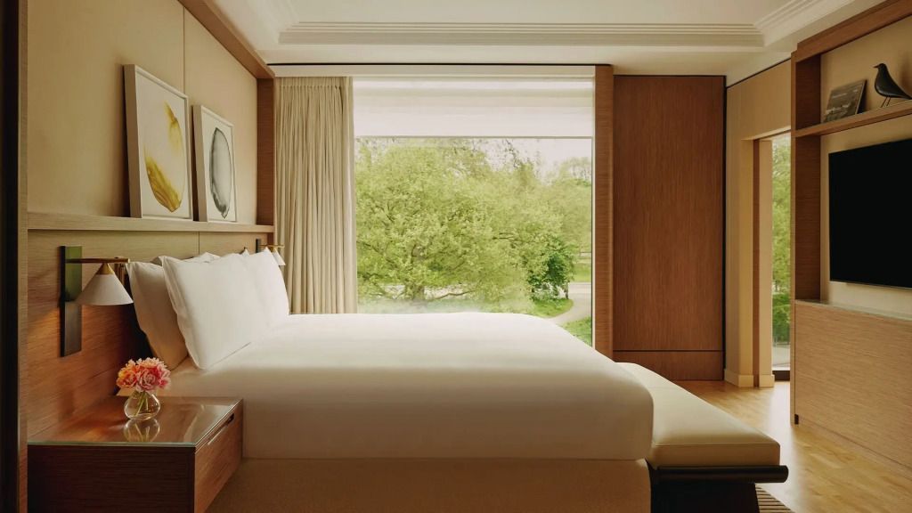 Helles und gemütliches Schlafzimmer mit großem Fenster und Ausblick auf üppiges Grün.