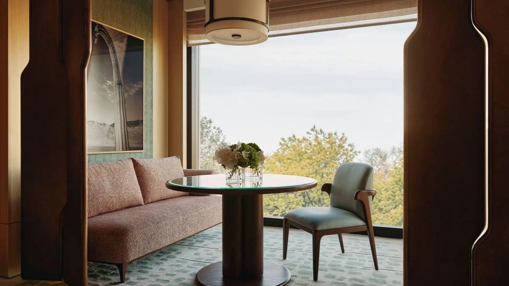Gemütlicher Sitzbereich in einer Suite mit Tisch, Stuhl und großer Fensterfront