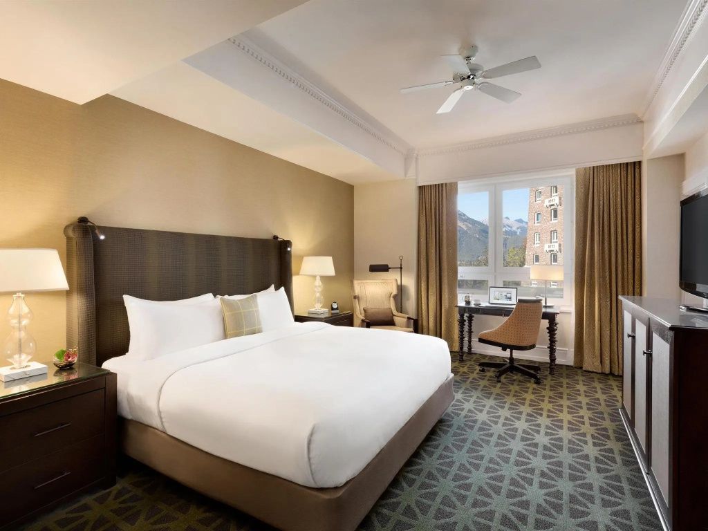 Helles Deluxe Doppelzimmer im Fairmont Banff Springs mit großem Bett und Bergblick.