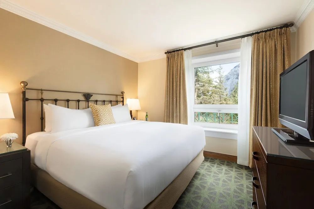 Helles Schlafzimmer mit großem Doppelbett, Fenster mit Bergblick und stilvollen Vorhängen