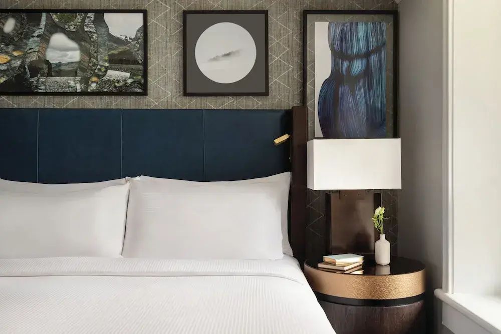 Doppelbett mit Nachttischlampen und stilvoller Kunst im Hintergrund