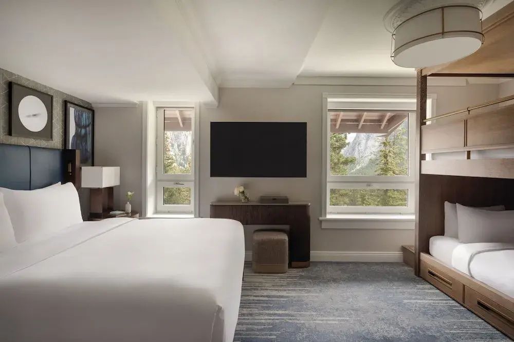 Geräumiges Zimmer mit großem Bett und Blick aus dem Fenster auf die Berge