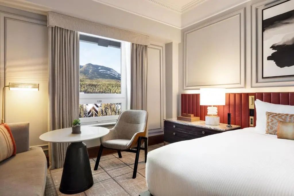 Helles Hotelzimmer mit gemütlicher Sitzgelegenheit und Bergblick im Fairmont Banff Springs
