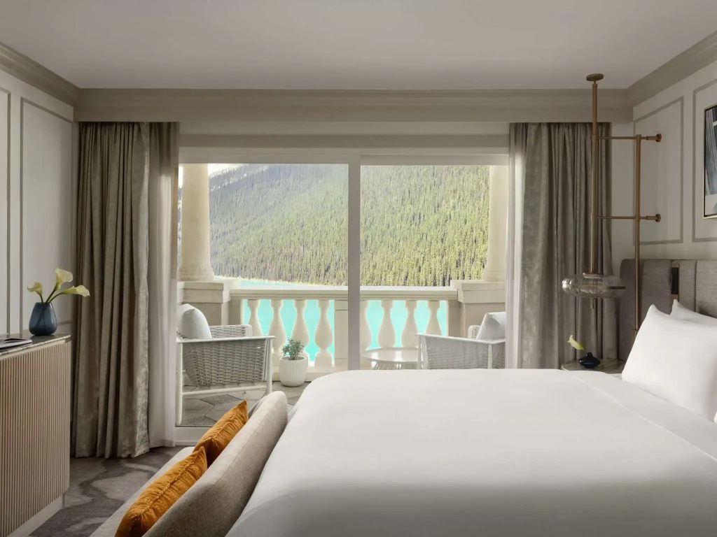 Helles Schlafzimmer mit Blick auf See und Berge durch große Fenster.