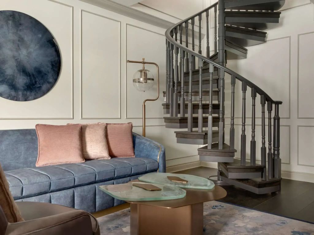Eleganter Wohnbereich mit Wendeltreppe und stilvollem Sofa.
