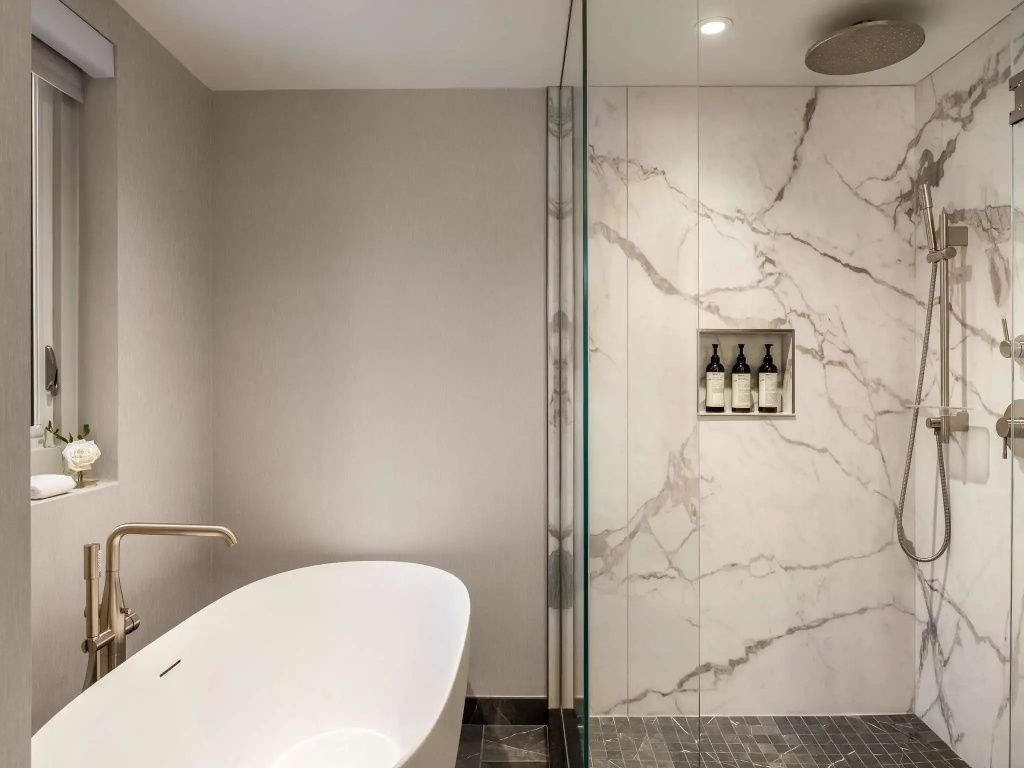 Elegantes Badezimmer mit freistehender Badewanne und Duschkabine aus Marmor