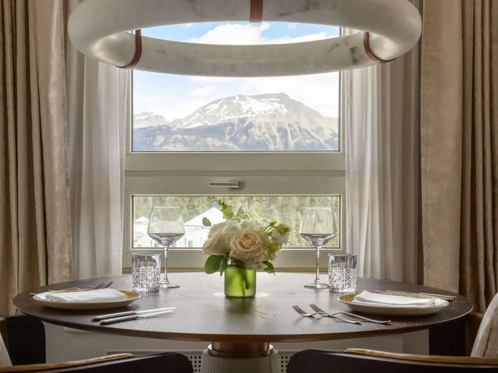 Esstisch mit Bergblick durch ein großes Fenster und stilvoller Dekoration