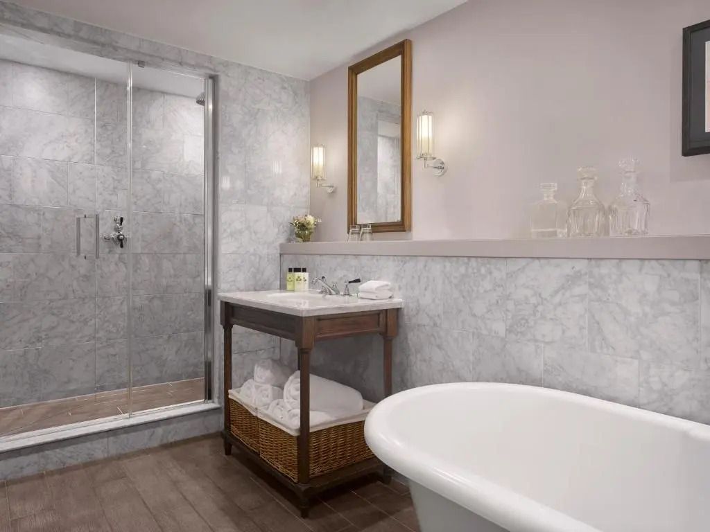 Modernes Badezimmer in einer Suite mit freistehender Badewanne und großem Spiegel.