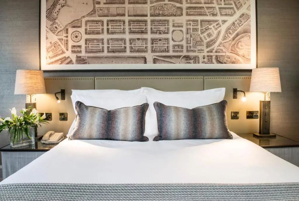 Einladendes Bett in stilvollem Doppelzimmer mit kunstvoller Wanddekoration