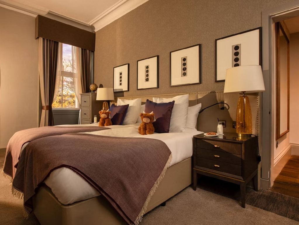 Elegantes Doppelbett mit Kunstwerken und dekorativen Kissen in der Somerville Suite.