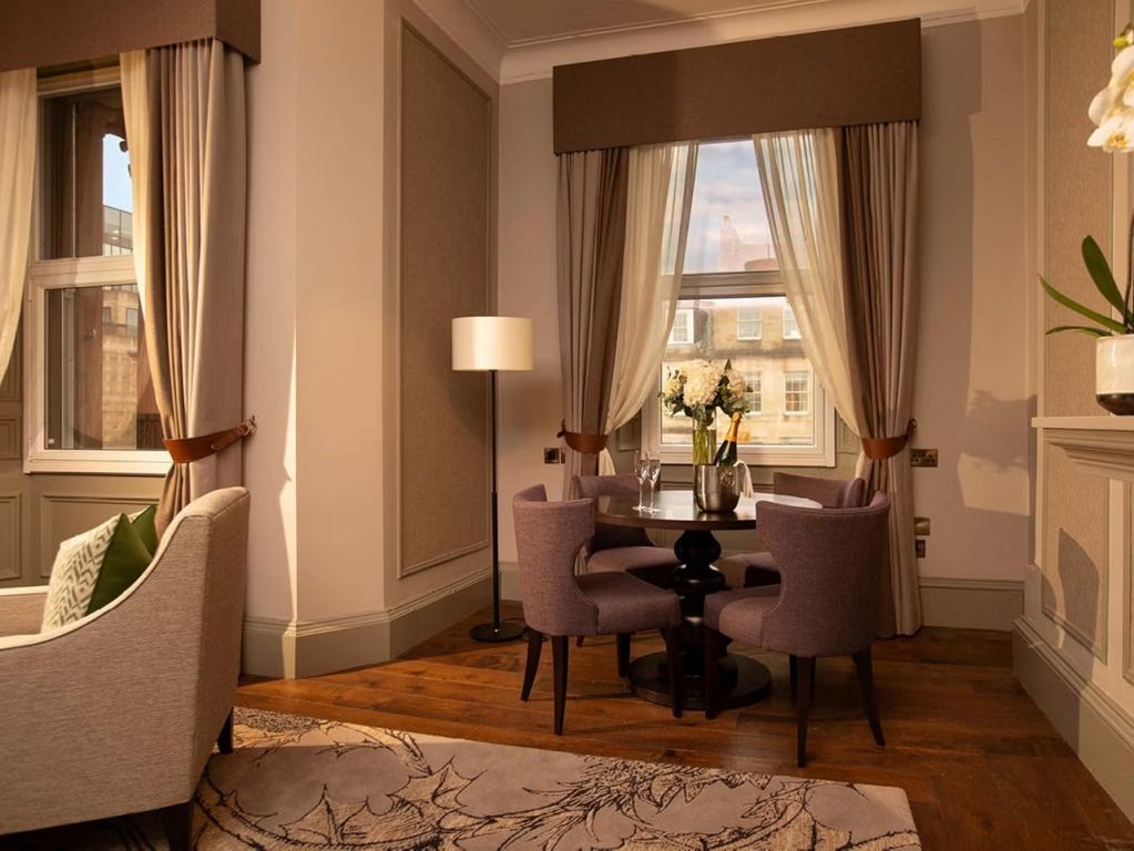 Gemütlicher Sitzbereich mit Tischset und Blumendekoration nahe dem Fenster.