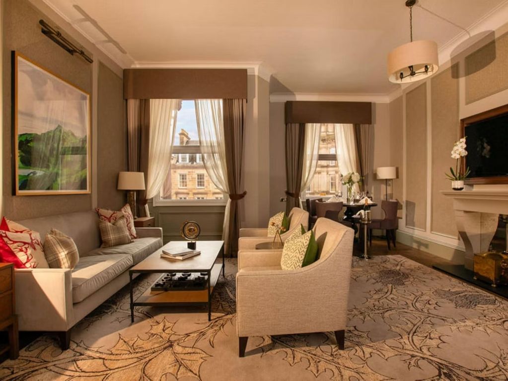 Heller Wohnbereich mit stilvollen Möbeln und großem Fenster in der Somerville Suite.