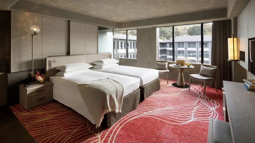 Modernes Hotelzimmer mit zwei Einzelbetten und heller Einrichtung.