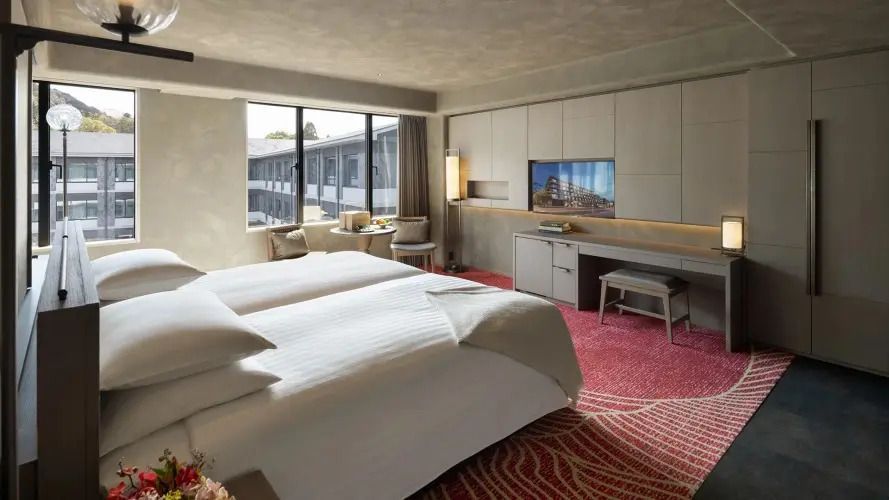 Geräumiges Zimmer mit zwei Einzelbetten und Arbeitsbereich.