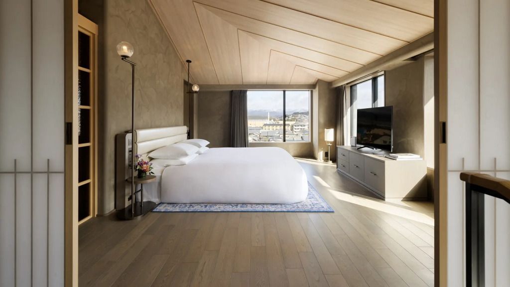 Geräumiges Schlafzimmer mit großem Doppelbett und modernen Lampen, Blick auf die Stadt durch ein Fenster.