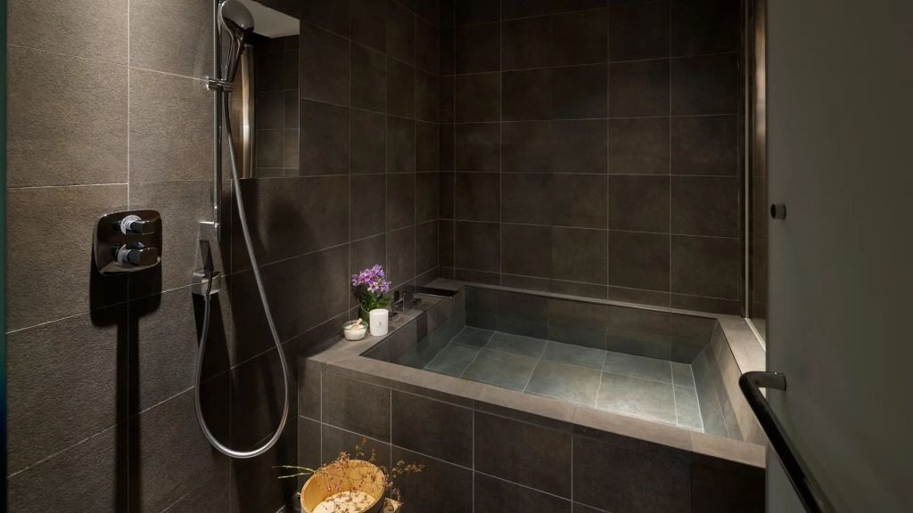 Modernes Badezimmer mit dunklen Fliesen, großer Badewanne und stilvollen Akzenten.