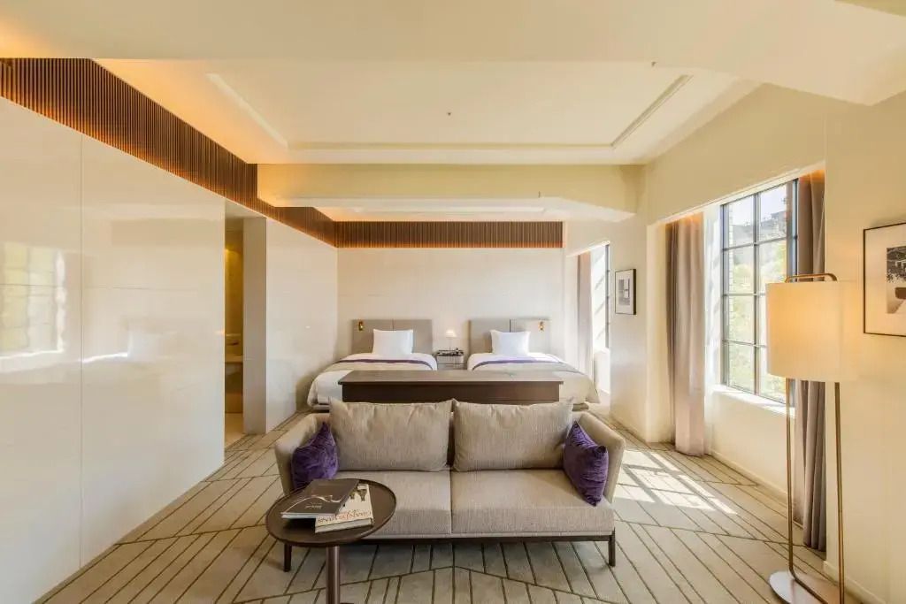Helle Hotelzimmer-Suite mit modernem Sofa, Doppelbett und stilvollem Design.