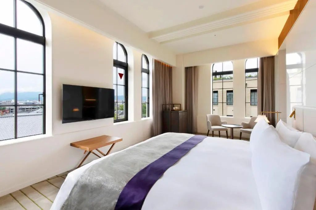 Hotelzimmer mit Doppelbett, Fernseher und Blick nach draußen.