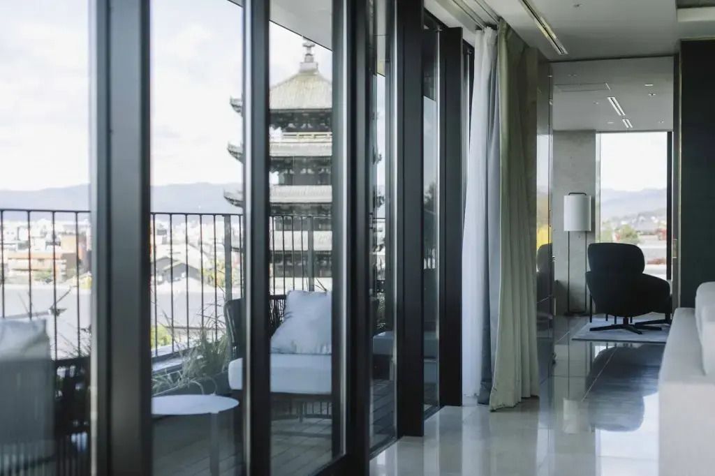 Balkon mit Sitzgelegenheiten und Blick auf eine Pagode durch raumhohe Fenster