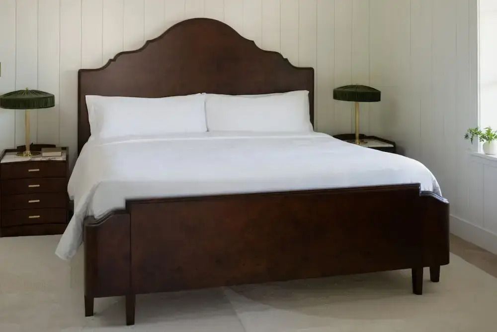 Großes Doppelbett mit dunklem Holzrahmen und minimalistischer Dekoration