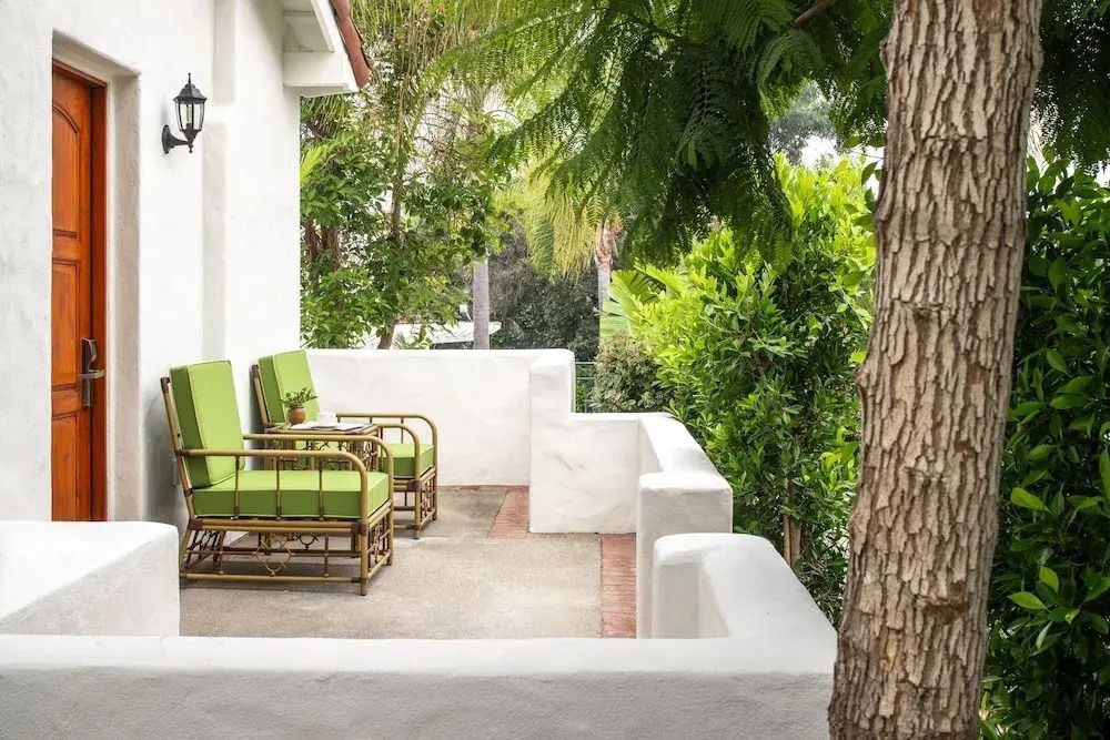 Terrasse mit grünen Sesseln und weißen Wänden umgeben von Pflanzen