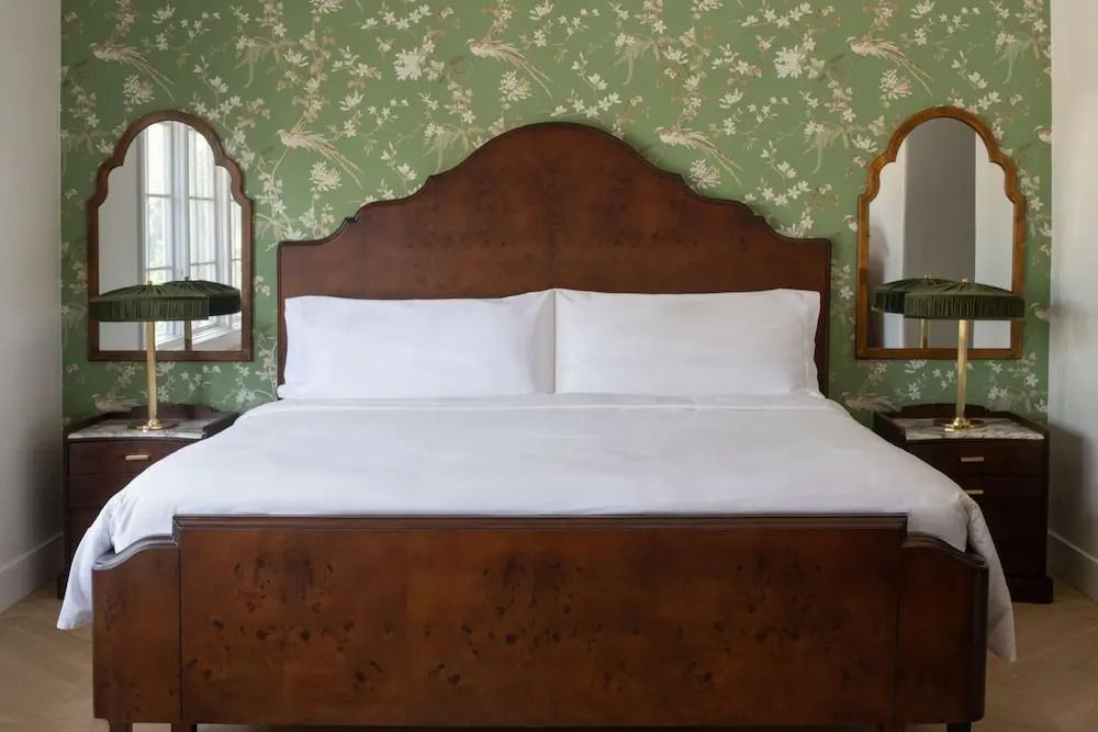 Doppelbett mit Holzrahmen und floralem Hintergrund in einem Premier Doppelzimmer.