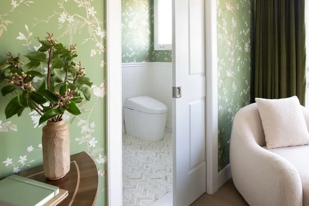 Kleines WC-Bad mit grüner Tapete und weißer Tür in elegantem Design.