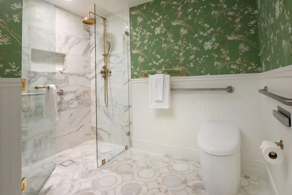 Dusche mit Glasabtrennung, Marmorwänden und floraler Tapete im luxuriösen Bad.