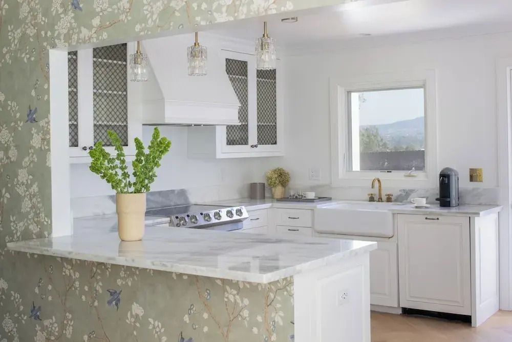 Moderne Küche mit hellem Marmortresen und Blumenakzent