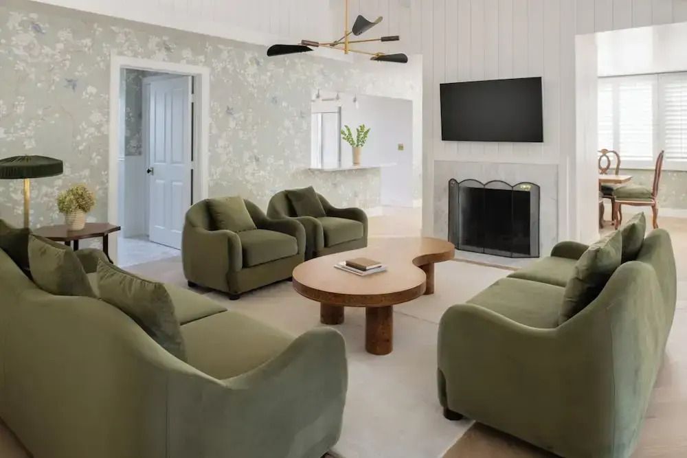 Wohnzimmer mit grünen Sesseln einem Kamin und eleganter Atmosphäre