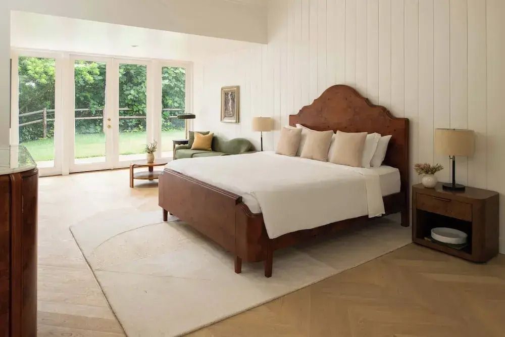 Stilvolles Schlafzimmer mit großem Bett, heller Einrichtung und Gartenblick