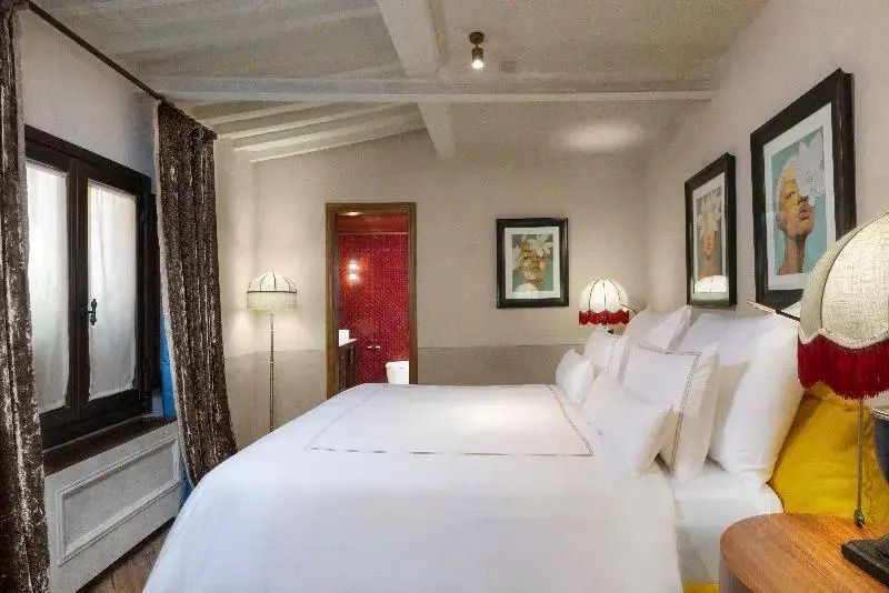 Gemütliches Schlafzimmer mit eleganter weißer Bettwäsche und dezenten Kunstwerken.