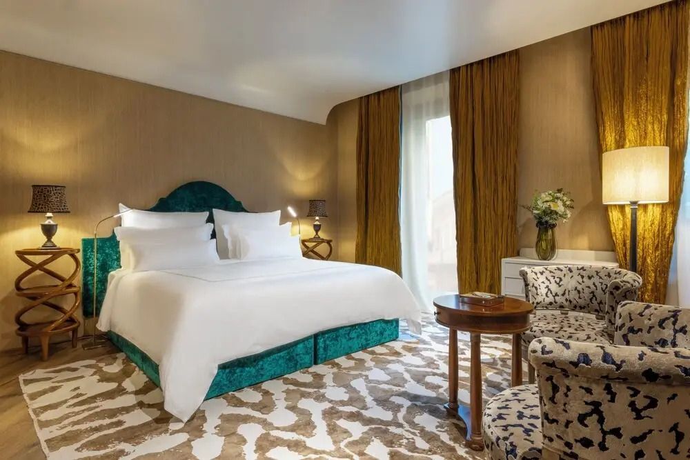 Elegantes Schlafzimmer mit türkisfarbenem Bett und gemustertem Teppich.