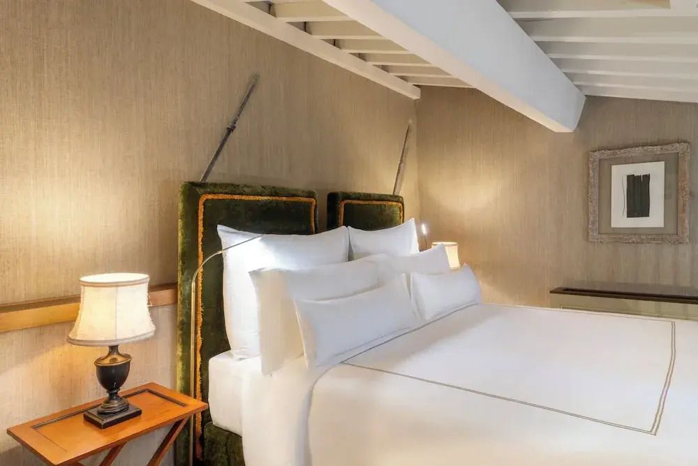 Komfortables Bett in einer stilvoll eingerichteten Suite mit heller Holzdecke.
