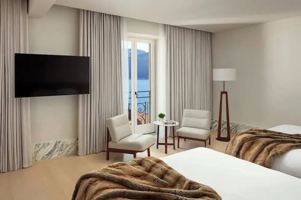 Helle Sitzecke mit Glasfenster und Seeblick im Hotelzimmer.