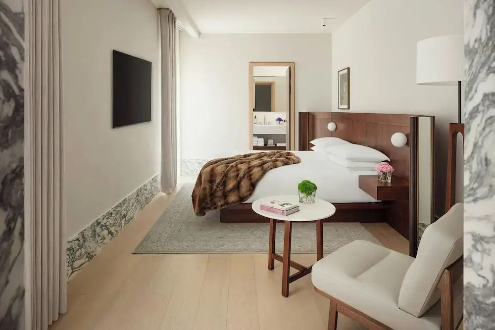 Geräumiges Doppelzimmer mit Holz- und Marmorelementen, und einem großen Fenster.