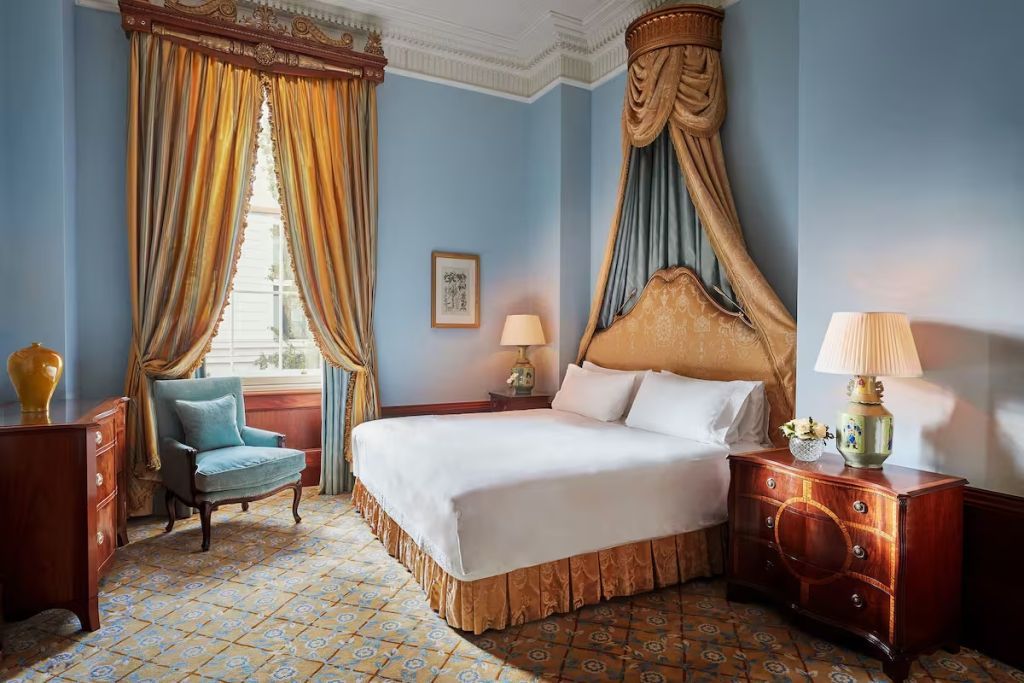 Luxuriöses Doppelbett in elegant eingerichtetem Zimmer mit opulenten Vorhängen