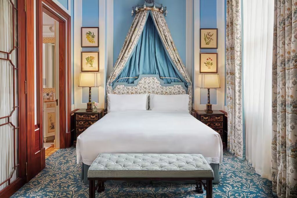 Stilvolle Suite mit Himmelbett und dekorativen Kissen in blauem Dekor.