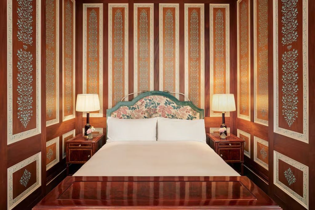 Elegantes Zimmer mit einem großen Doppelbett und klassischen Nachttischen in Holzoptik.