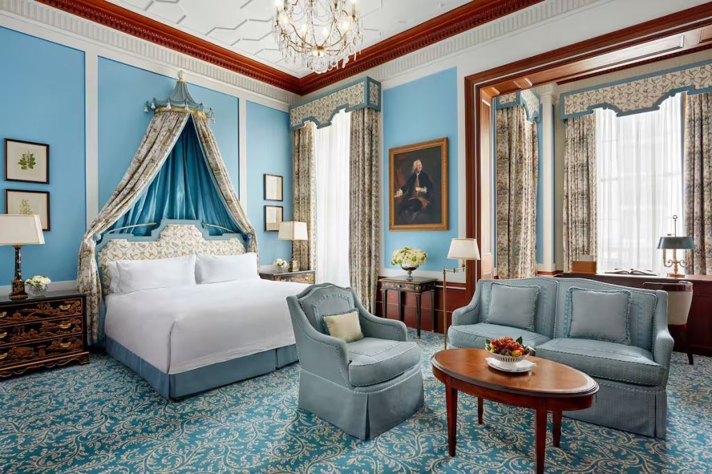 Großes, helles Zimmer mit prächtigem Himmelbett und luxuriöser Einrichtung in Blau und Gold.