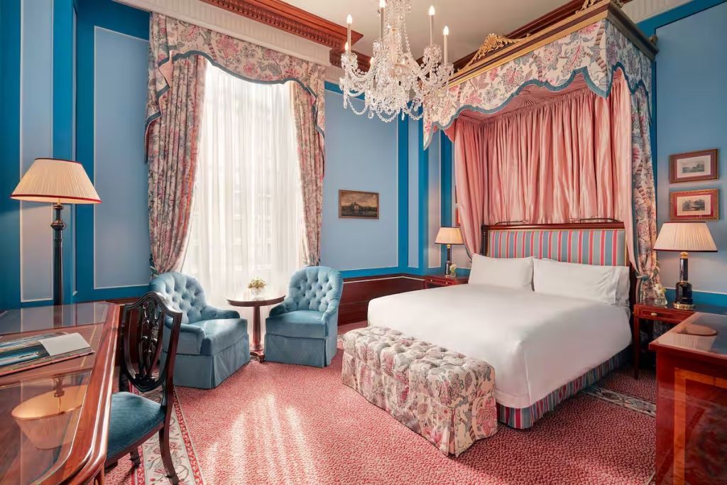 Elegantes Executive Doppelzimmer mit Kronleuchter und Blick auf blau dekorierte Wände.