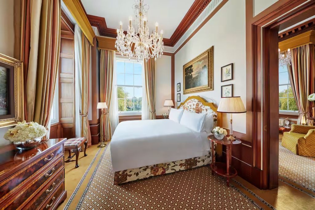 Elegantes Schlafzimmer mit Kronleuchter und großen Fenstern in der Hyde Park Corner Suite.