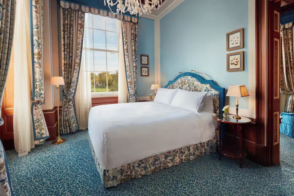 Luxuriöses Schlafzimmer in Blau mit Blick auf den Hyde Park durch große Fenster.