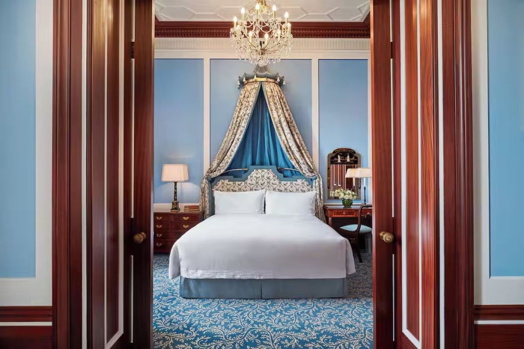 Elegantes Schlafzimmer mit blauem Baldachin und Kristallleuchter in der Park Doppel Suite.