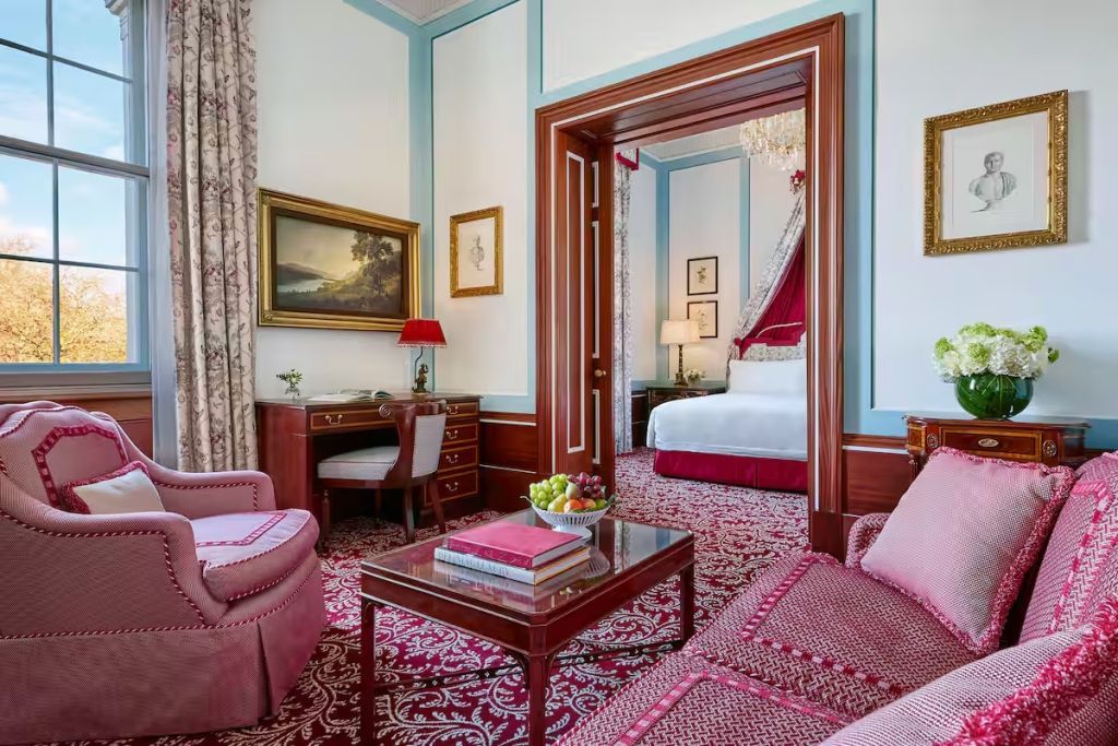 Wohnbereich mit eleganter roter Einrichtung und Blick ins Schlafzimmer der Park Doppel Suite.