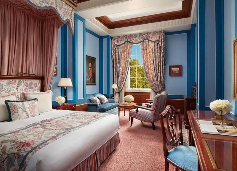Premier Zimmer mit luxuriösem Doppelbett, blauen Wänden und eleganten Vorhängen